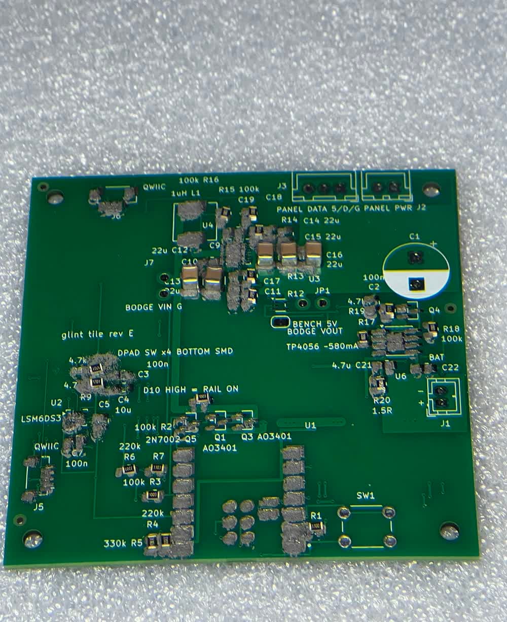 Stop-motion of a green circuit board being assembled, shot from above on a grey work surface. It starts bare with grey solder paste on the pads, then components appear a few at a time: capacitors, resistors, black chips, connectors along the top edge, and finally a silver processor module and USB-C port at the bottom.