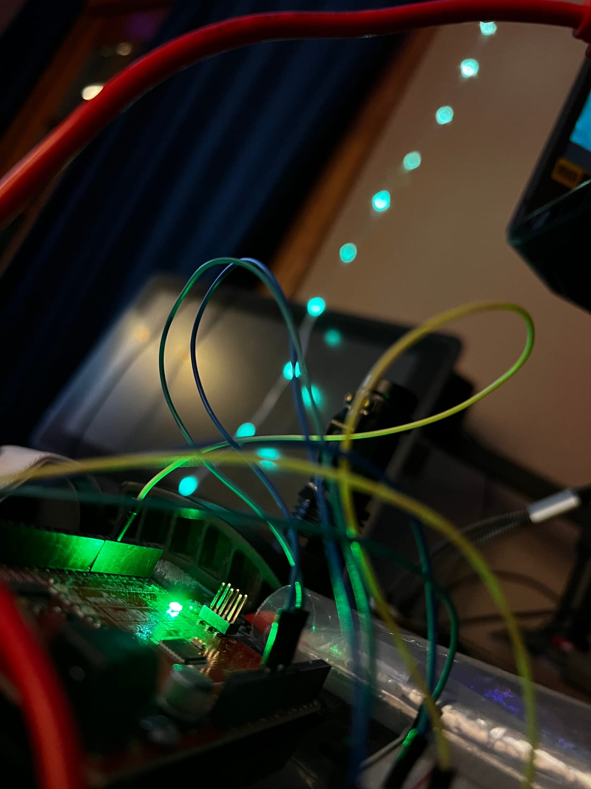 Addressable LED strands glowing green and cyan in a dim room, wired to a small microcontroller on a breadboard.
